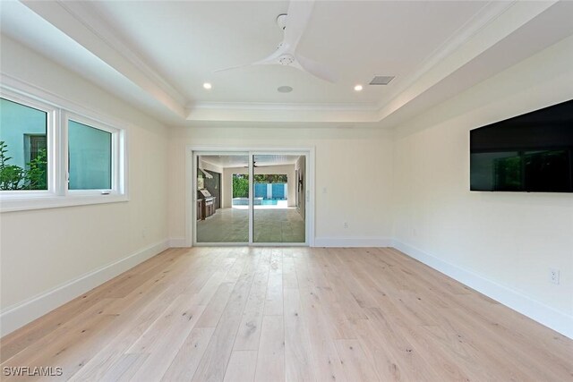 interior space with ceiling fan, light wood-type flooring, a raised ceiling, and ornamental molding