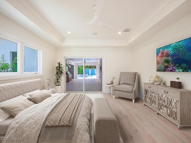 bedroom with ceiling fan, a tray ceiling, light wood-type flooring, and access to outside