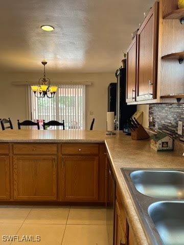 kitchen with open shelves, brown cabinetry, a peninsula, and a sink