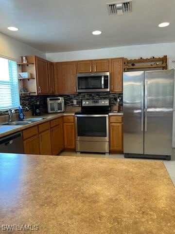 kitchen featuring stainless steel appliances, a sink, visible vents, and decorative backsplash