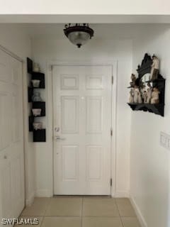 doorway to outside featuring light tile patterned floors and baseboards