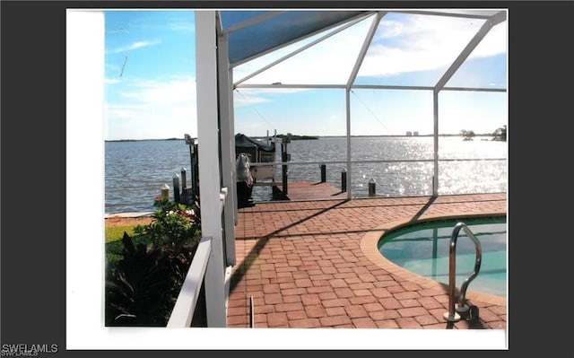 view of swimming pool with a lanai, a dock, a water view, and a patio area