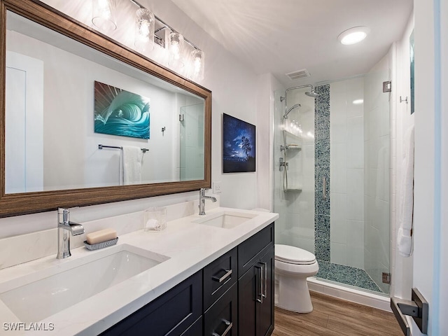 bathroom with wood-type flooring, vanity, toilet, and a shower with door