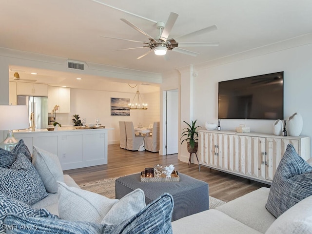 living room featuring ceiling fan with notable chandelier, crown molding, and hardwood / wood-style flooring