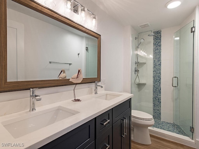 bathroom with an enclosed shower, vanity, toilet, and hardwood / wood-style flooring