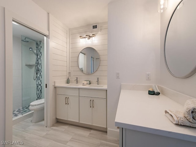 bathroom featuring a tile shower, vanity, and toilet