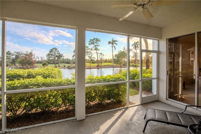 unfurnished sunroom featuring a wealth of natural light, a water view, and ceiling fan