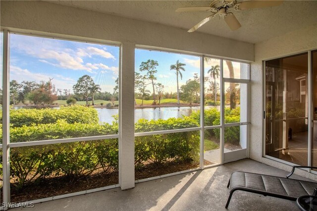 unfurnished sunroom featuring a water view and a ceiling fan