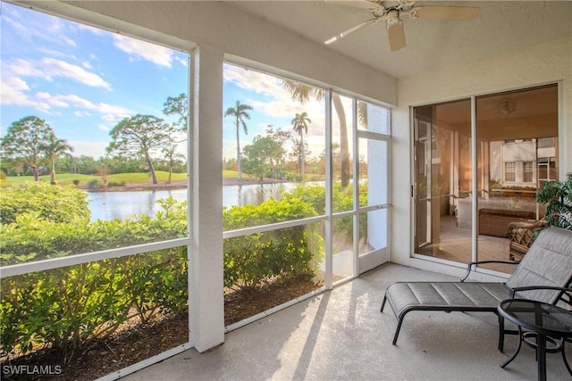 sunroom / solarium featuring a ceiling fan and a water view