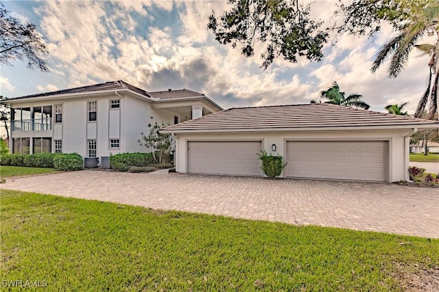 mediterranean / spanish-style house featuring stucco siding, a front lawn, and driveway