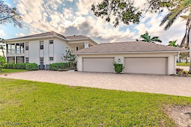 view of front of house with stucco siding, driveway, a tiled roof, and a front yard