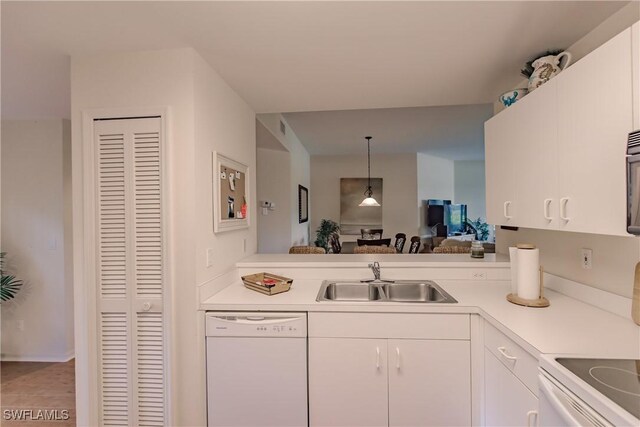 kitchen with white dishwasher, light countertops, white cabinets, and a sink