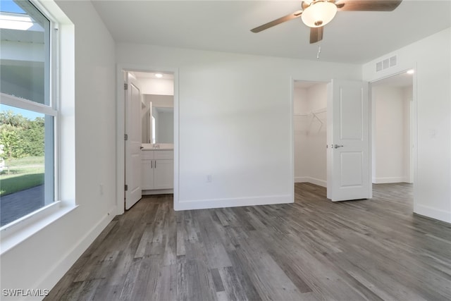 unfurnished bedroom featuring wood-type flooring, multiple windows, and ceiling fan