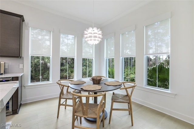 dining room with beverage cooler, crown molding, a chandelier, and light wood-type flooring