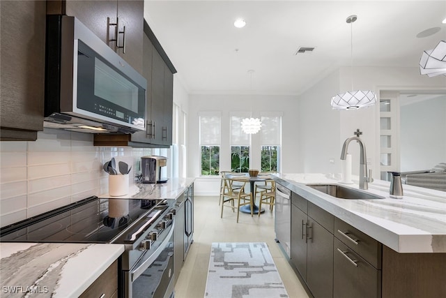 kitchen featuring appliances with stainless steel finishes, hanging light fixtures, sink, and decorative backsplash