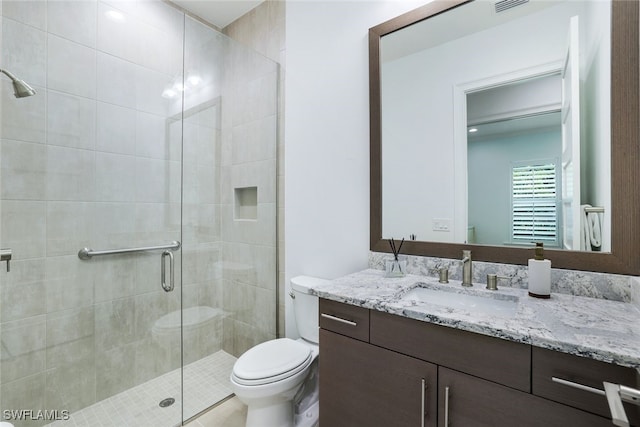 bathroom with a shower with door, vanity, and toilet