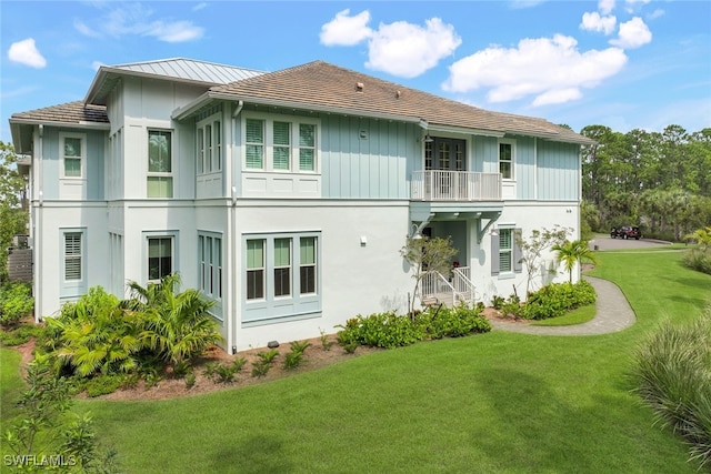 back of property with a balcony and a lawn