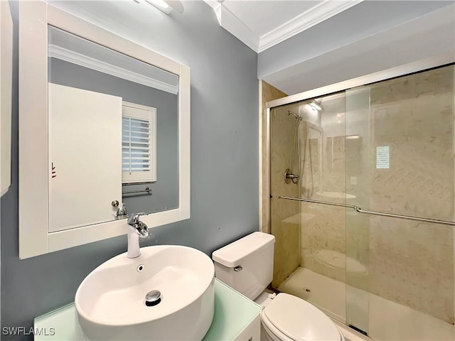 bathroom featuring toilet, a shower with shower door, ornamental molding, and sink