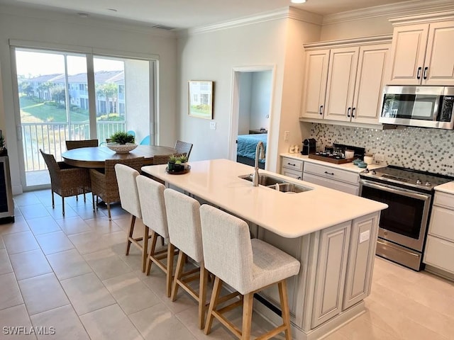 kitchen with appliances with stainless steel finishes, an island with sink, decorative backsplash, sink, and a breakfast bar area