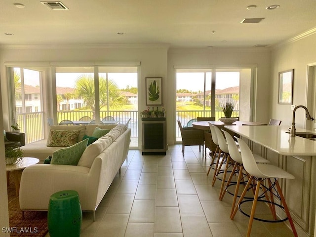 tiled living room with ornamental molding, a water view, and sink