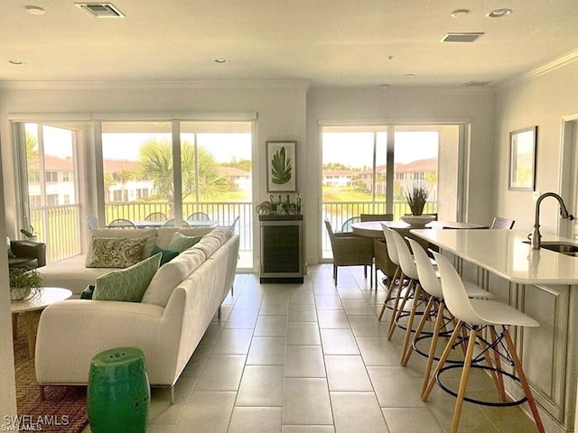 living room with crown molding, a water view, sink, and light tile patterned floors