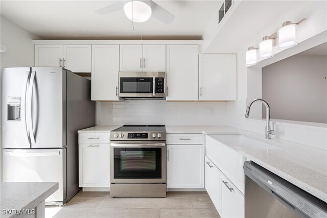 kitchen featuring light stone countertops, stainless steel appliances, light hardwood / wood-style flooring, and white cabinetry