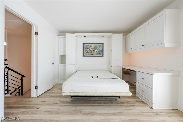 bedroom with built in desk and light hardwood / wood-style flooring