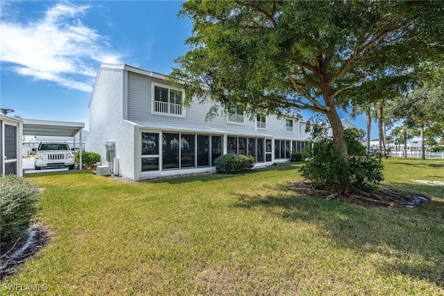 rear view of property with a lawn and a sunroom