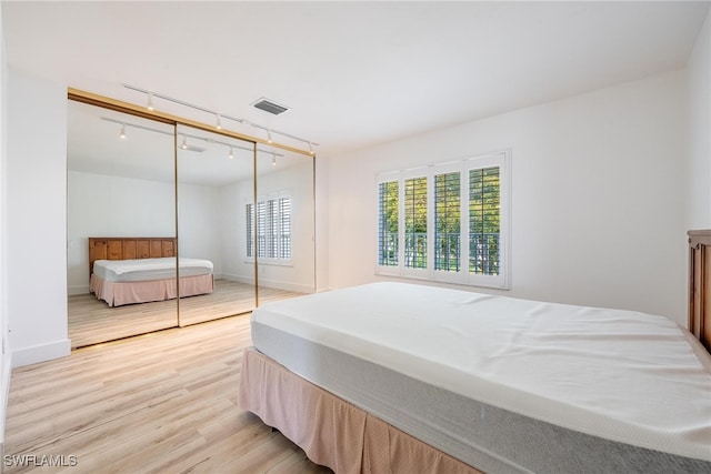 bedroom featuring a closet, light wood-type flooring, and track lighting