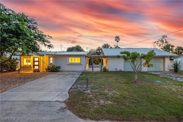 ranch-style home with a yard, a porch, and a garage