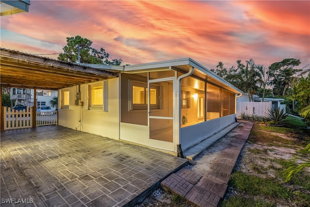 property exterior at dusk featuring a patio area