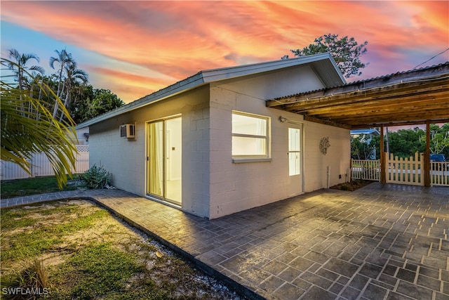 property exterior at dusk with a wall mounted air conditioner and a patio