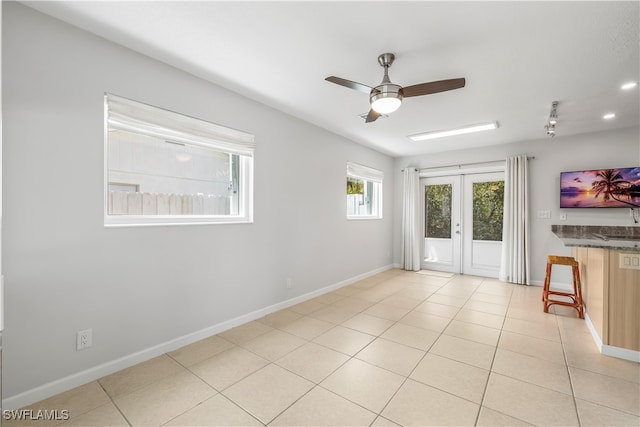 unfurnished room with ceiling fan, light tile patterned floors, and french doors