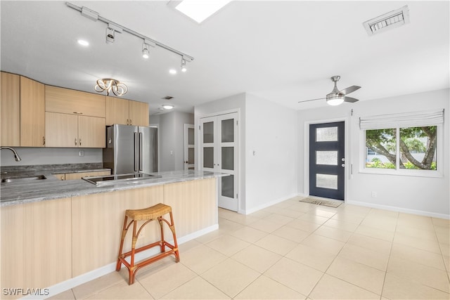 kitchen with a kitchen breakfast bar, kitchen peninsula, light brown cabinets, sink, and high end fridge