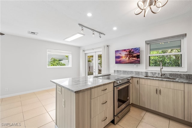 kitchen with stainless steel range with electric cooktop, light brown cabinets, sink, and a wealth of natural light