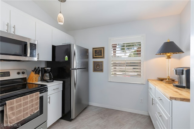 kitchen featuring appliances with stainless steel finishes, wood counters, hanging light fixtures, light hardwood / wood-style floors, and white cabinets