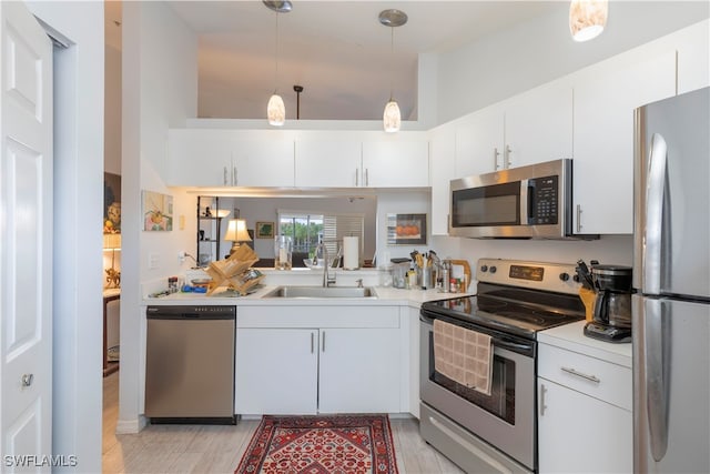 kitchen featuring sink, white cabinetry, hanging light fixtures, and stainless steel appliances