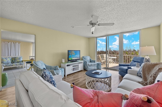 living room with a textured ceiling, ceiling fan, and light hardwood / wood-style flooring