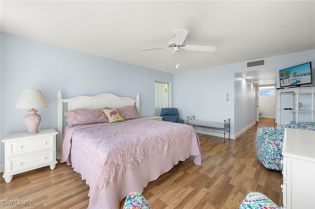 bedroom featuring ceiling fan, a textured ceiling, and light hardwood / wood-style floors