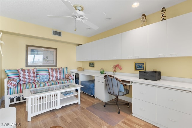 office space featuring light wood-type flooring, built in desk, and ceiling fan