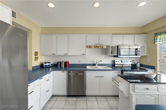 kitchen featuring stainless steel appliances, a textured ceiling, sink, light tile patterned floors, and white cabinetry