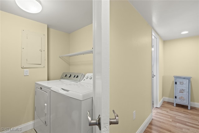 laundry area featuring washing machine and clothes dryer, light hardwood / wood-style flooring, and electric panel