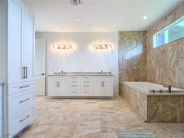 bathroom featuring tiled tub and vanity