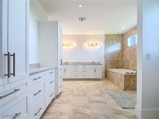 bathroom featuring a relaxing tiled tub and vanity