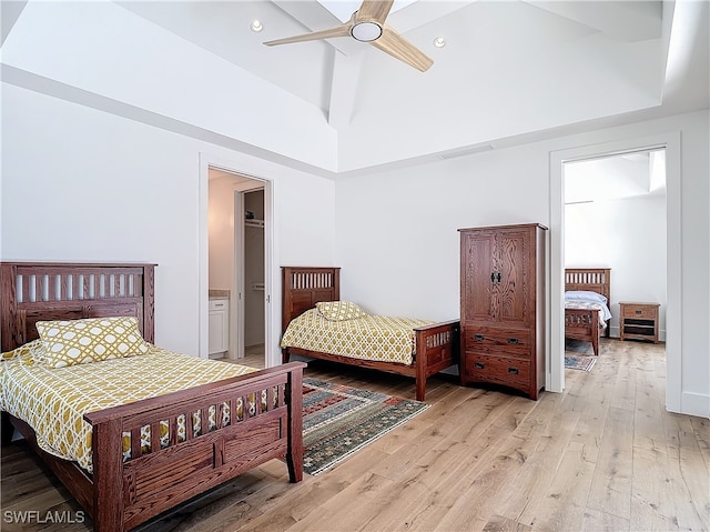 bedroom featuring a towering ceiling, a closet, ceiling fan, light hardwood / wood-style flooring, and a walk in closet