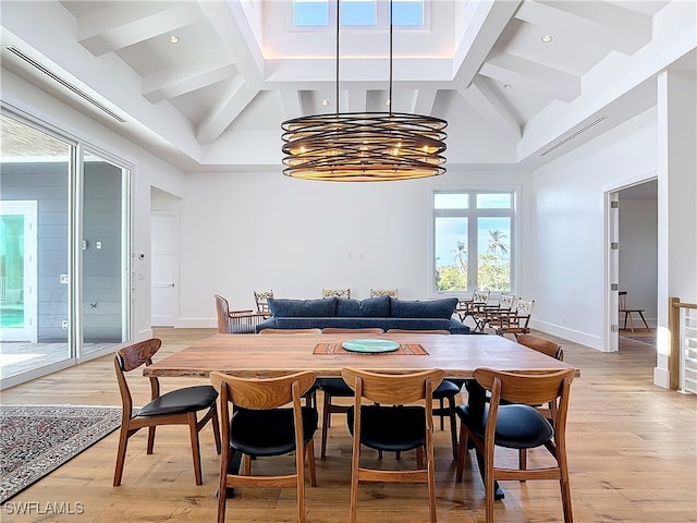 dining space featuring light wood-type flooring, high vaulted ceiling, and a notable chandelier