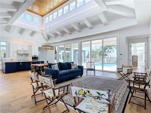 living room featuring beamed ceiling, light hardwood / wood-style flooring, and high vaulted ceiling