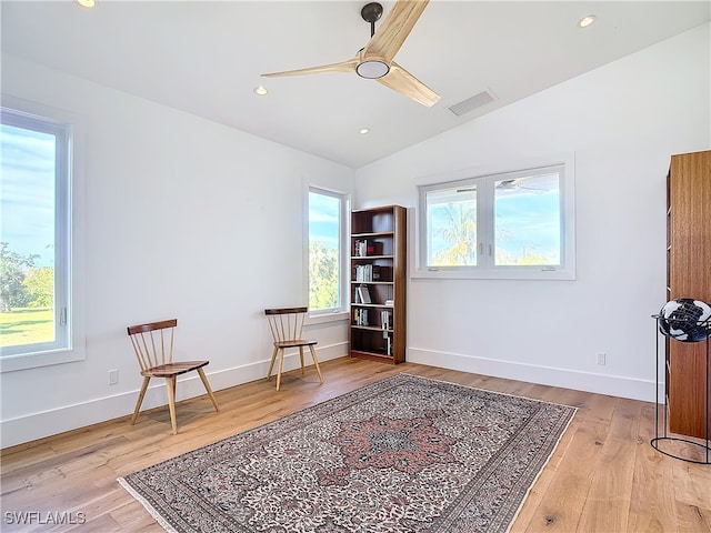 living area with ceiling fan, lofted ceiling, and light hardwood / wood-style floors