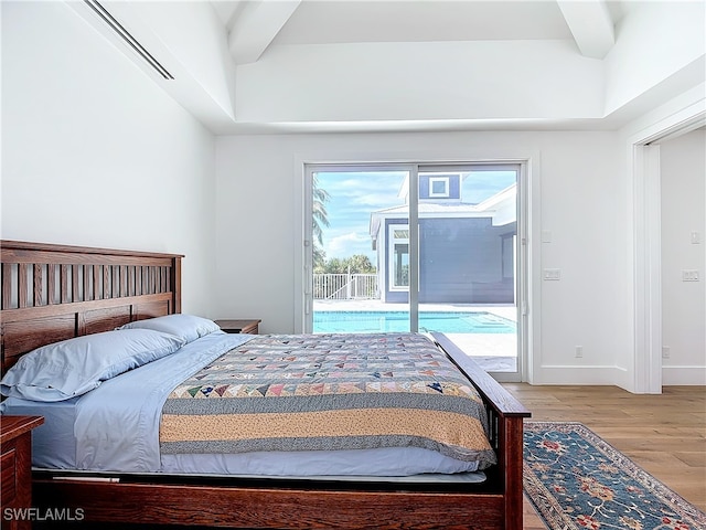 bedroom featuring beamed ceiling, light hardwood / wood-style floors, and access to exterior