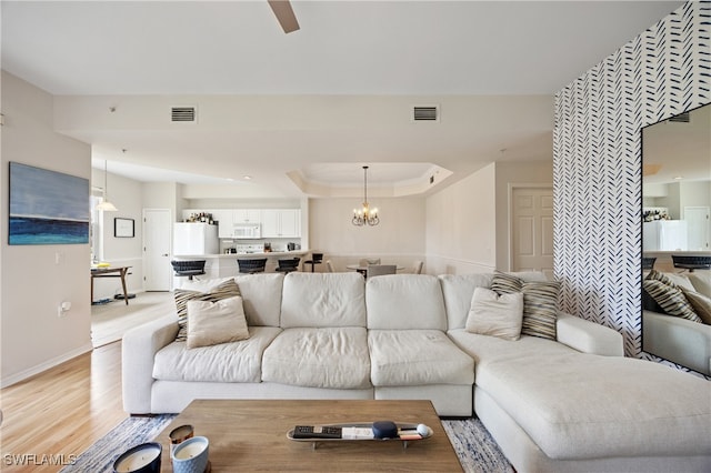 living room with ceiling fan with notable chandelier and light wood-type flooring